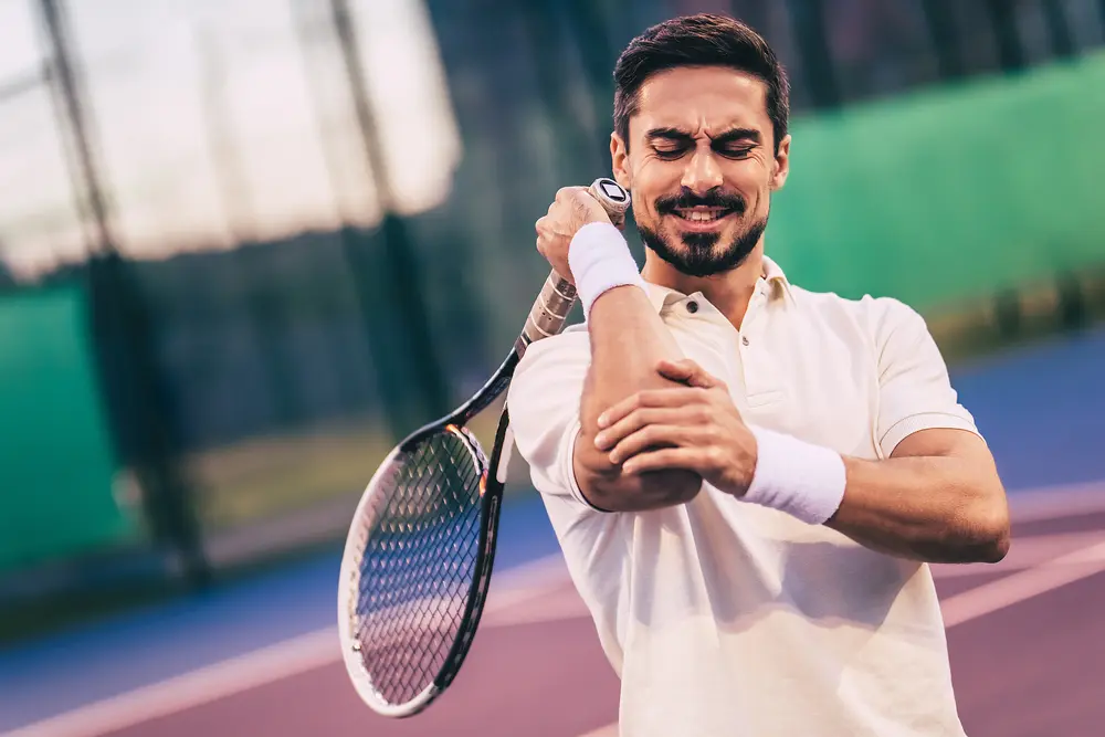 man playing tennis with hurt elbow