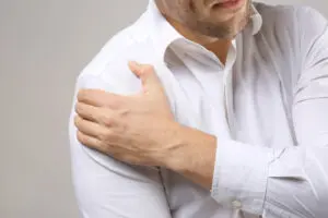 man in white shirt experiencing shoulder pain