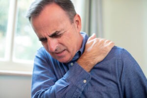mature man suffering from frozen shoulder at home