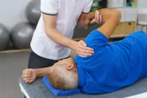 Physiotherapist doing shoulder exercises with an elderly male patient to increase his mobility and restore functionality