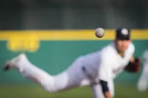 A baseball in motion with pitcher in background.