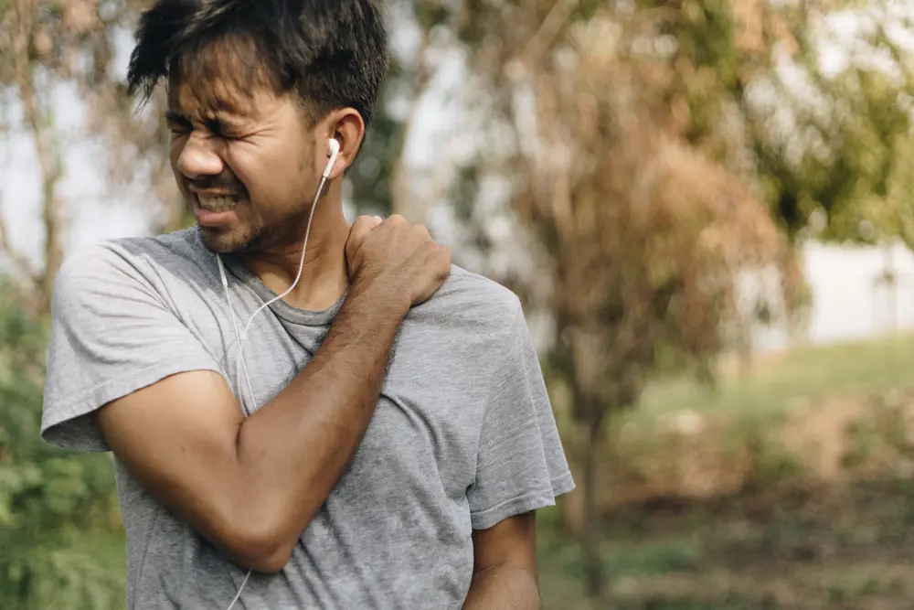 young asian man have shoulder pain after running and exercising