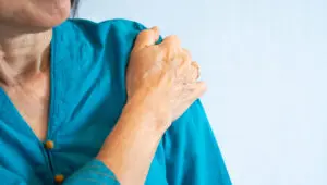 older woman in blue blouse getting shoulder pain