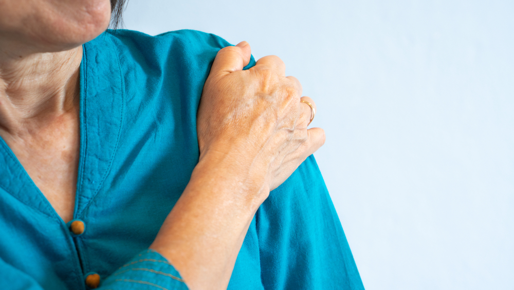 older woman in blue blouse getting shoulder pain