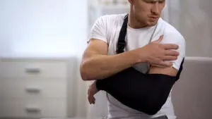 Man wearing arm sling feeling pain in shoulder