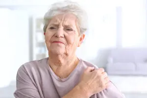 Elderly woman suffering from pain in shoulder at home