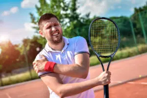 man with tennis racket in hand with shoulder pain