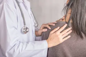 Doctor examining a women with shoulder blade pain